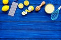 Cook lemon curd. Sweet cream in bowl, fruits, kitchen utensils grater and whisk on blue wooden background top view copy Royalty Free Stock Photo