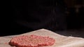 Cook makes meat medallions for burgers. Chef in black food gloves makes cutlet. Cutlets are leveled in steel ring in an