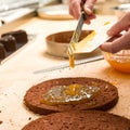 Cook making layer chocolate cake with marmalade