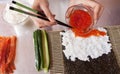 Cook making sushi rolls with caviar