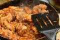 The cook mixes fried chicken with spices in a pan