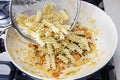 The cook mixes the pasta with a thick sauce and vegetables