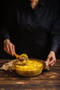 Cook mixes potato casserole on a wooden background