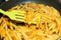 A cook mixes a spatula with fried potatoes in a frying pan in sunflower oil