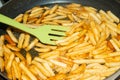 A cook mixes a spatula with fried potatoes in a frying pan in sunflower oil