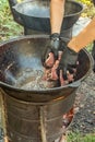 Cook places the chopped meat in a cast-iron cauldron on an outdoor wood-burning stove. Royalty Free Stock Photo