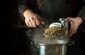 The cook pours dry green lentils from a bowl into a saucepan. Dark space for recipe. The idea of preparing a delicious lunch in