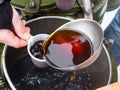 The cook pours hot tea from an army cauldron into a plastic cup