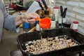 Cook pours oil into mushrooms with onions in square frying pan