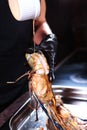 The cook pours sauce over giant freshwater shrimps. Grilled shrimp. Photo on a black background. Vertical photo. Cooking concept