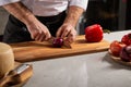 Cook male precisely slicing red onions on wooden cutting board in restaurant kitchen Royalty Free Stock Photo