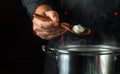 The cook prepares dumplings in a pan in the kitchen. Close-up of a chef hand holding a spoon. The concept of cooking a deliciou