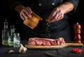 Cook prepares raw veal meat. Before baking, the chef adds salt to the beef. National dish is being prepared in the kitchen Royalty Free Stock Photo