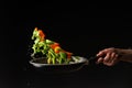 Cook prepares vegetables on a black background, oriental cuisine, tasty and healthy food, recipe book, menu, cooking