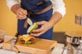 Cook preparing burger adding the sauce on green bun. Royalty Free Stock Photo