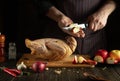 The cook is preparing duck for lunch. Raw duck with apples and spices on the kitchen table. Chef cuts an apple Royalty Free Stock Photo