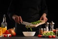 Cook preparing food by the chef, the cook cuts green beans on a background of vegetables. Black background for design, vegetation