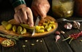 The cook is preparing a salad of pickled cucumbers for breakfast. The chef cuts a pickled cucumber into pieces with a knife. Royalty Free Stock Photo