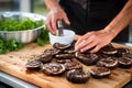 a cook prepping portobello mushrooms for grilling