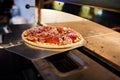 Cook putting Italian pizza to bake in oven