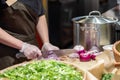 Cook's hands in cellophane gloves cutting red onion into thin slices. Cooking vegetable ingredients Royalty Free Stock Photo