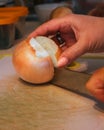 A cook's hands cut a large onion in half