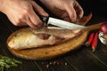 Cook hands with a knife before cleaning raw carp fish on kitchen table. Cooking a delicious fish dish according to a popula Royalty Free Stock Photo