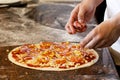 Cook`s hands putting salsiccia sausage on tomato base pizza. Royalty Free Stock Photo