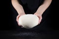 Cook`s hands and raw dough close-up on a black background. The concept of baking and pastry Royalty Free Stock Photo