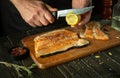 The cook seasoning a trout steak with fresh lemon on the kitchen table. Pink salmon is a delicious fish for cooking dinner. The