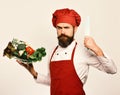 Cook with serious face in burgundy uniform holds salad ingredients Royalty Free Stock Photo