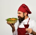 Cook with shocked face in burgundy uniform holds baked dish