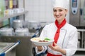 Cook showing plate with food in commercial kitchen of canteen