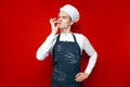 Cook shows gesture of good taste on a red isolated background, guy in the form of a chef makes a hand sign Royalty Free Stock Photo