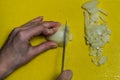 Cook slicing onions with a knife on a yellow cutting board