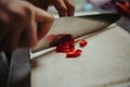 Cook slicing red chili on a chopping board