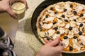 A cook sprinkles sesame seeds on homemade pizza during cooking