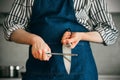 The cook is standing in the kitchen sharpening a knife blade with a whetstone Royalty Free Stock Photo