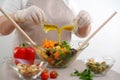 salad in glass bowl from two jugs stream oil sauce with mustard and honey ingredients front tablecloth olives tomatoes Royalty Free Stock Photo