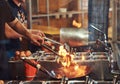 Cooking process in an Asian restaurant. Cook is stirring vegetables in a wok on a flame.