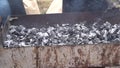 Cook stirs burnt coals in an iron grill