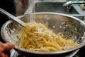 cook straining pasta over a sink