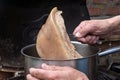 Cook takes a piece of slowly cooked rind meat out of the pot to make a stock sauce in a rustic kitchen, copy space, selected focus