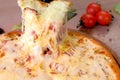 Cook takes a slice of cheese and bacon pizza with a gloved hand. Hand close-up.