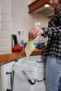 The cook throwing food peels in a compost bin for fermentation. Responsible female person recycling organic leftovers in a bokashi