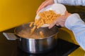 Cook throwing macaroni into a pot of boiling water