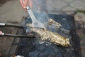 The cook turns the baked fish on the net with a metal spatula