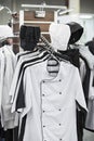 Cook uniform in a restaurant on a hanger, white and black uniforms, shirts and hats