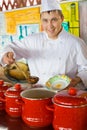 Cook in uniform spoon imposes soup in plate