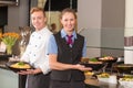 cook and waitress from catering service posing in front of buffet Royalty Free Stock Photo